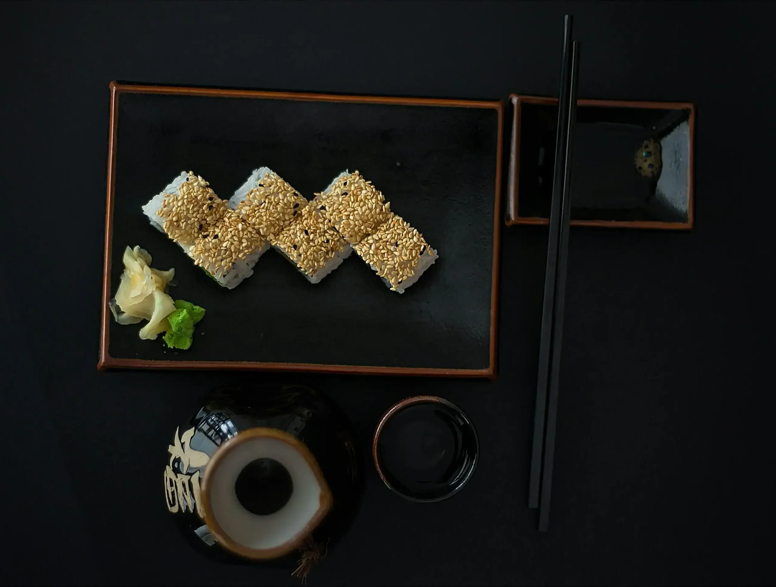 tres uramaki en un plato con palillos y salsa de soja